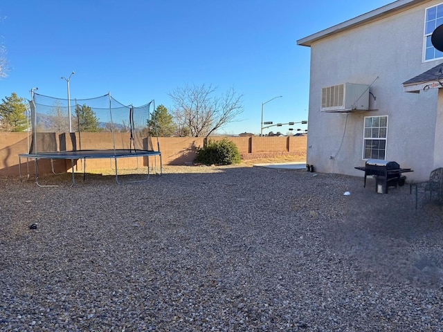 view of yard with a fenced backyard, a trampoline, and central AC unit