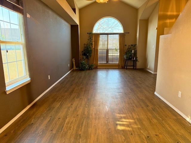 empty room featuring lofted ceiling, wood finished floors, and baseboards