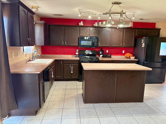 kitchen with visible vents, a kitchen island, light countertops, black appliances, and a sink