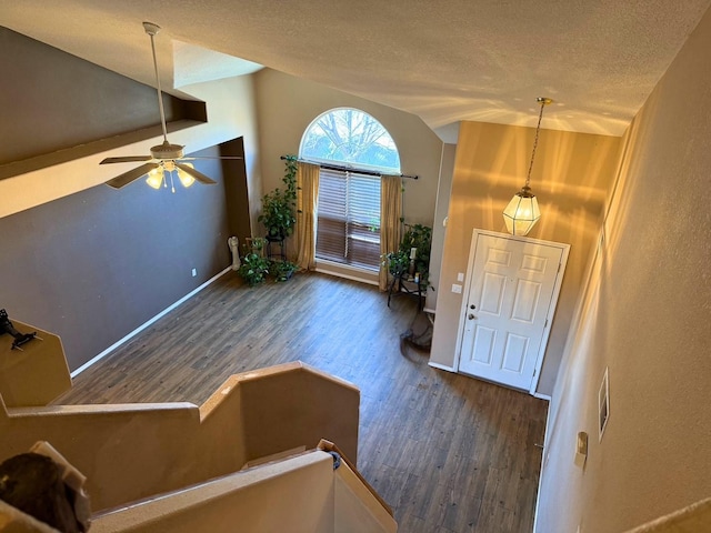 foyer featuring vaulted ceiling, a textured ceiling, wood finished floors, and baseboards