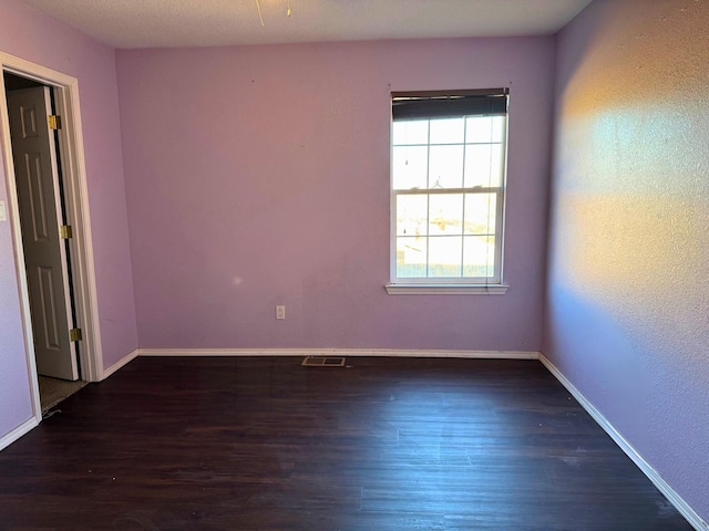 unfurnished room with baseboards, visible vents, and wood finished floors