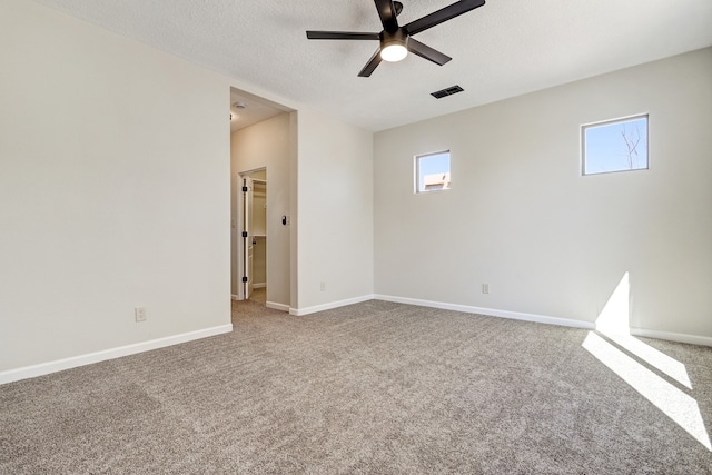 spare room with baseboards, visible vents, ceiling fan, a textured ceiling, and carpet flooring