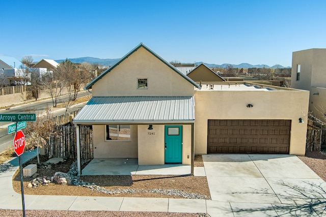 view of front of house with metal roof, a mountain view, a garage, concrete driveway, and stucco siding