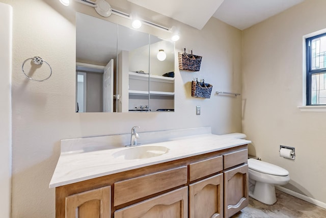 bathroom with vanity, toilet, and baseboards