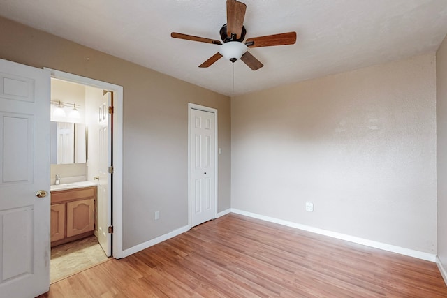 unfurnished bedroom with light wood-style floors, a closet, baseboards, and a sink