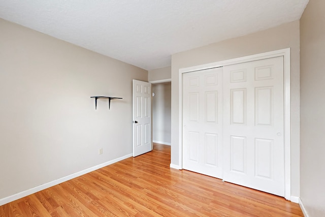 unfurnished bedroom with baseboards, a closet, and light wood-style floors