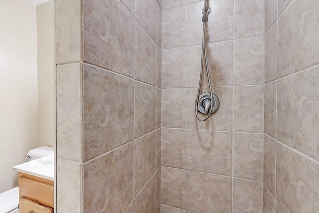 full bathroom with a tile shower, vanity, and toilet