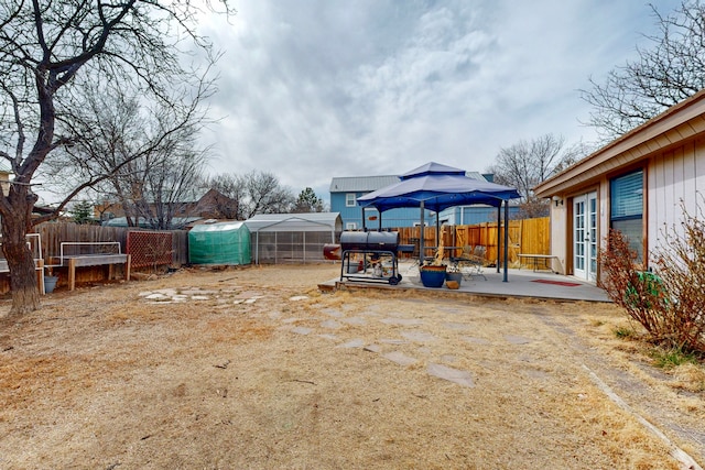 view of yard featuring a fenced backyard, an outbuilding, a patio, and french doors