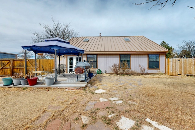 rear view of house with metal roof and fence