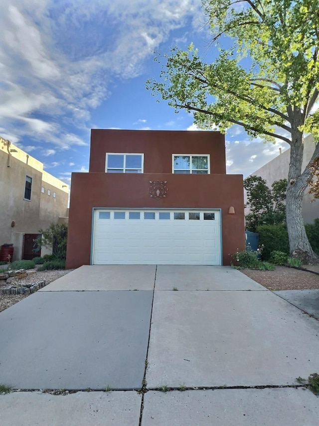 3228 El Trebol, Santa Fe, NM 87507 - pueblo-style house with an attached garage, concrete driveway, and stucco siding