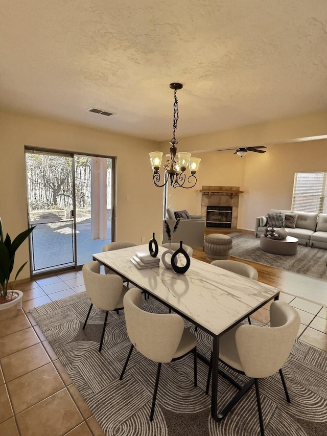 dining area featuring visible vents, a textured ceiling, and a tile fireplace