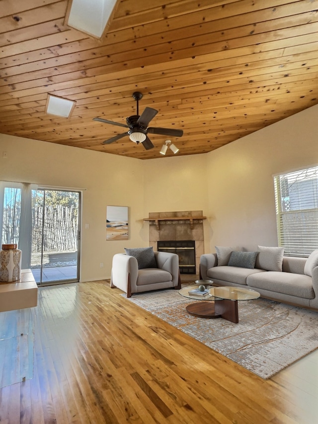 living room with ceiling fan, a fireplace, wood ceiling, lofted ceiling with skylight, and wood-type flooring