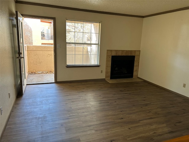 unfurnished living room featuring ornamental molding, a tile fireplace, a textured ceiling, and wood finished floors