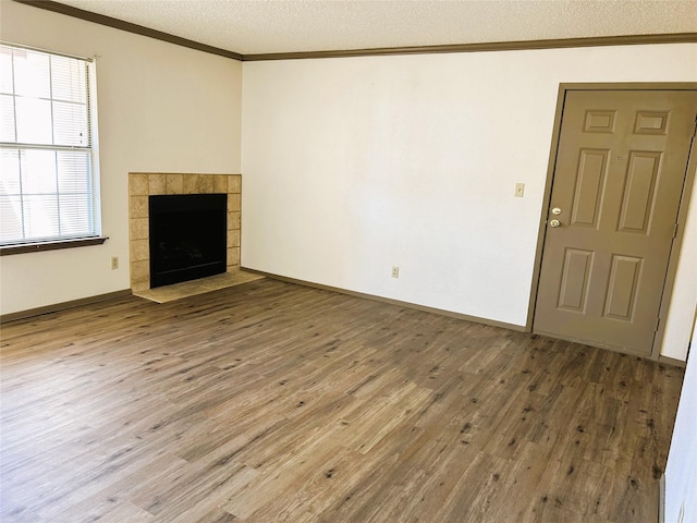 unfurnished living room featuring crown molding, wood finished floors, a fireplace, and a textured ceiling