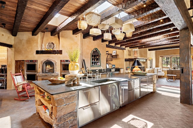 kitchen with open floor plan, brick floor, wooden ceiling, and beam ceiling