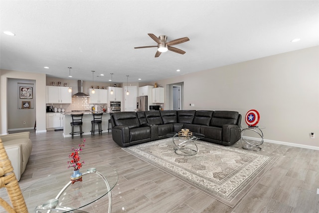 living area with light wood-style floors, baseboards, a ceiling fan, and recessed lighting