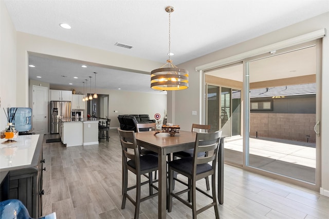 dining area featuring light wood finished floors, visible vents, a notable chandelier, and recessed lighting