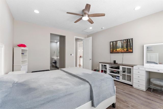 bedroom featuring recessed lighting, a textured ceiling, wood finished floors, and ensuite bathroom