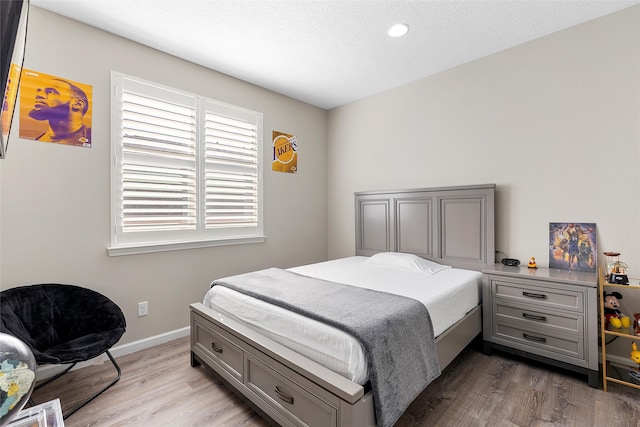 bedroom with a textured ceiling, wood finished floors, and baseboards