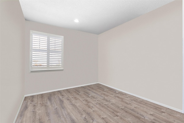 spare room with a textured ceiling, baseboards, and wood finished floors