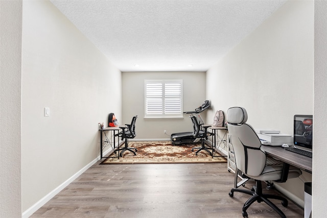 home office with a textured ceiling, baseboards, and wood finished floors