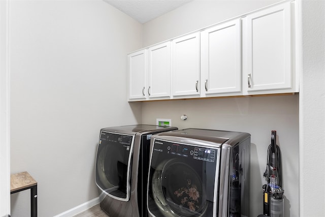 clothes washing area with baseboards, cabinet space, washing machine and clothes dryer, and wood finished floors