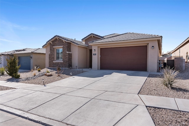 view of front of house featuring concrete driveway, stone siding, a tile roof, an attached garage, and stucco siding