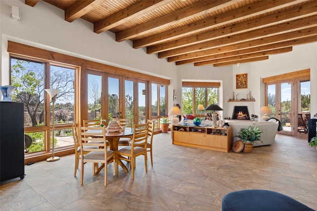 dining space featuring a lit fireplace, french doors, beam ceiling, and wood ceiling