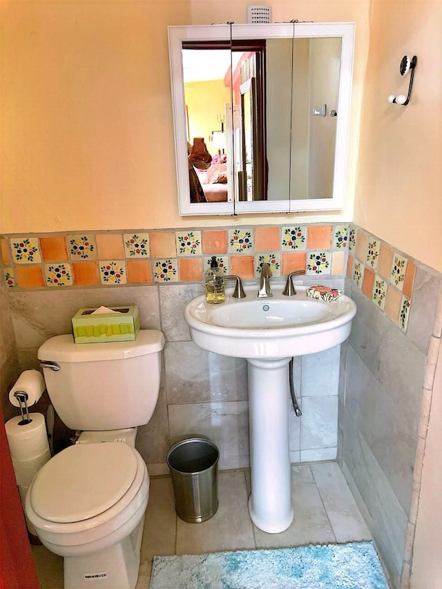 bathroom featuring toilet, wainscoting, tile walls, and tile patterned floors