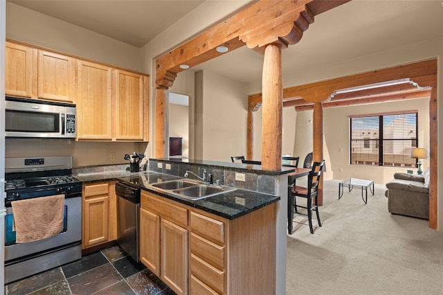 kitchen featuring stainless steel appliances, open floor plan, light brown cabinets, a sink, and a peninsula