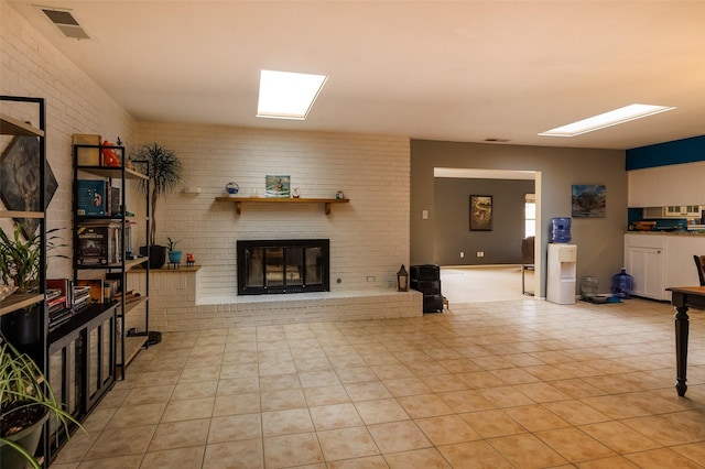 living room with light tile patterned floors, brick wall, a fireplace, and visible vents