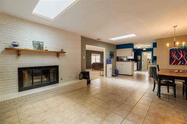 living room featuring a brick fireplace, light tile patterned floors, and a chandelier