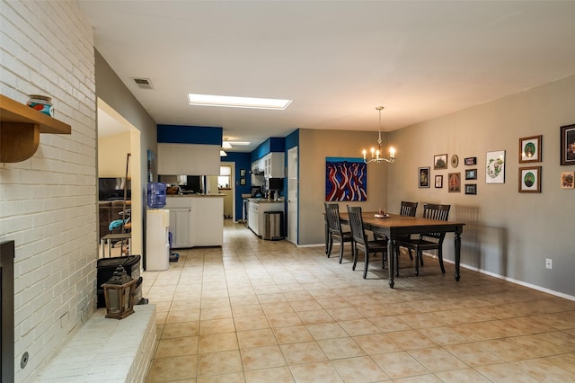 dining room featuring light tile patterned floors, brick wall, visible vents, and an inviting chandelier