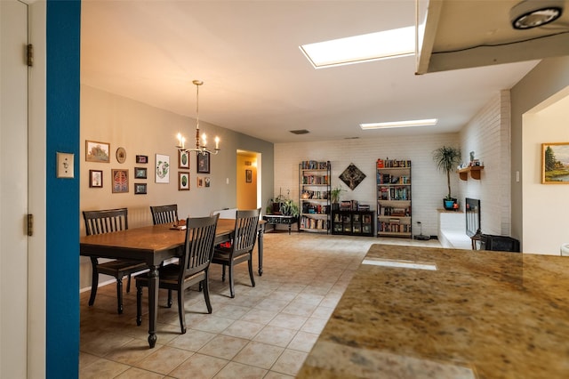 dining room featuring a notable chandelier, brick wall, and light tile patterned floors