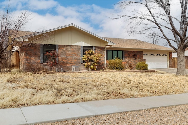 ranch-style house with an attached garage, fence, board and batten siding, and brick siding