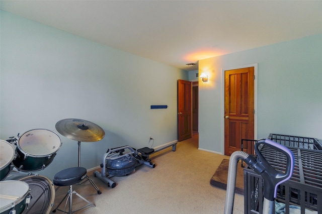 exercise area with baseboards, visible vents, and light colored carpet