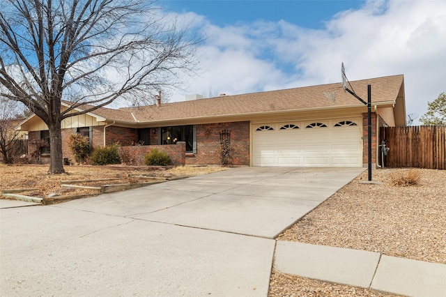 ranch-style house with a garage, concrete driveway, brick siding, and fence