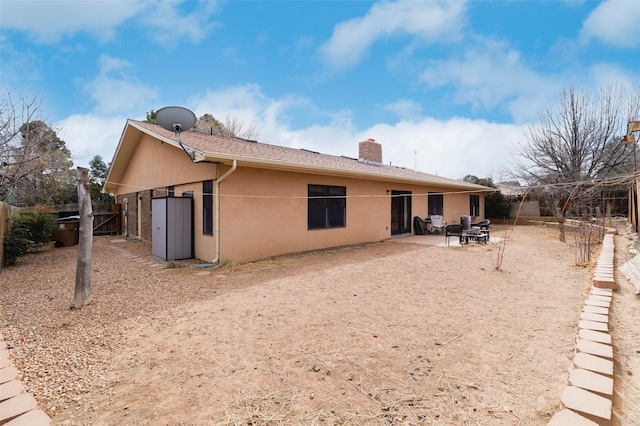 back of house featuring a fenced backyard, a patio, a chimney, and stucco siding