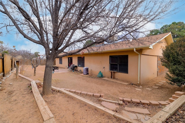 back of house featuring fence and stucco siding