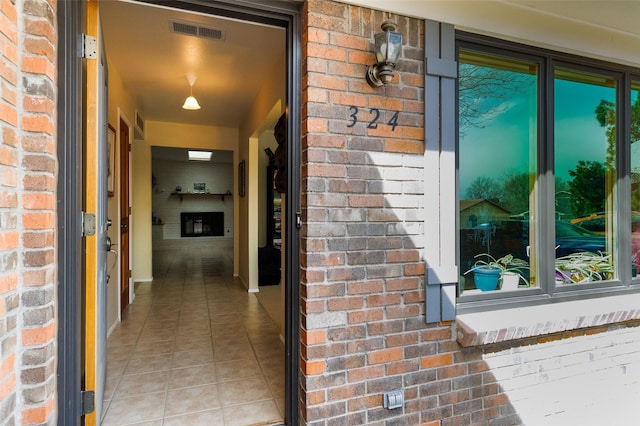 doorway to property featuring visible vents and brick siding