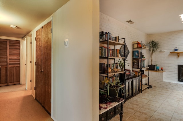 hall featuring brick wall, visible vents, and tile patterned flooring