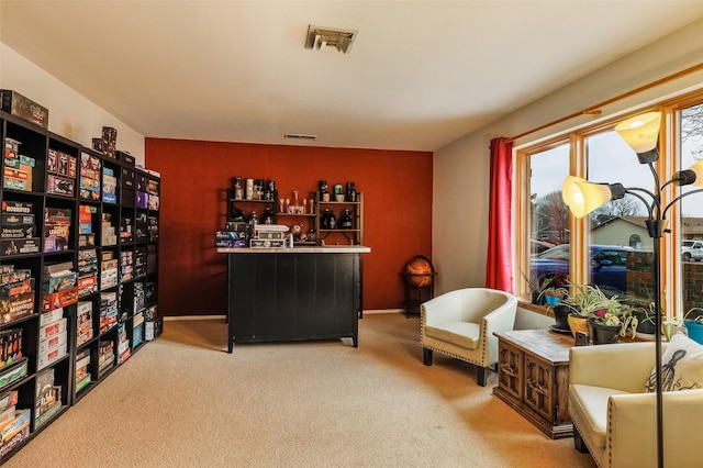 living area with baseboards, visible vents, and light colored carpet