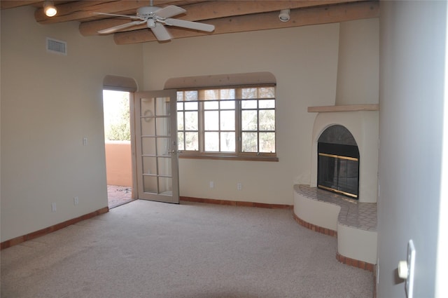 unfurnished living room with a fireplace, visible vents, baseboards, beamed ceiling, and carpet