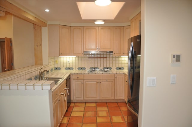 kitchen with freestanding refrigerator, tile counters, a sink, and light brown cabinetry