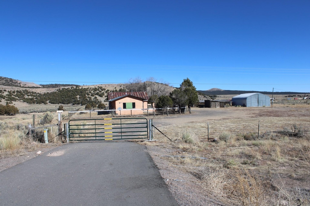 view of road featuring a mountain view, a gate, a gated entry, and aphalt driveway