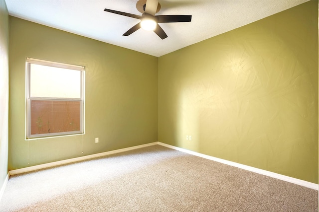 spare room with carpet, a ceiling fan, and baseboards