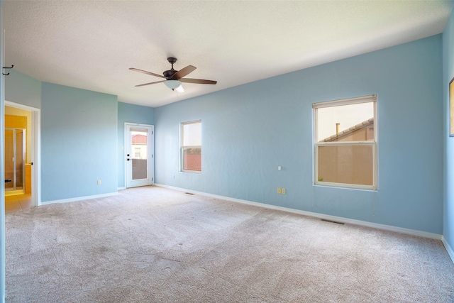 carpeted empty room with visible vents, ceiling fan, a textured ceiling, and baseboards