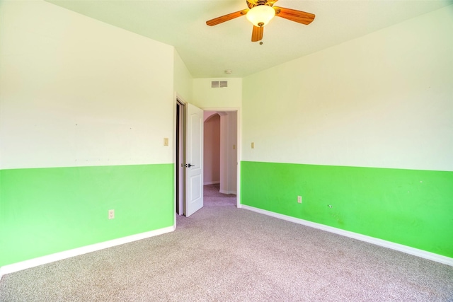 carpeted spare room with baseboards, visible vents, and ceiling fan