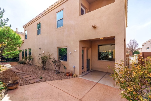 rear view of property featuring a patio area, a tile roof, and stucco siding