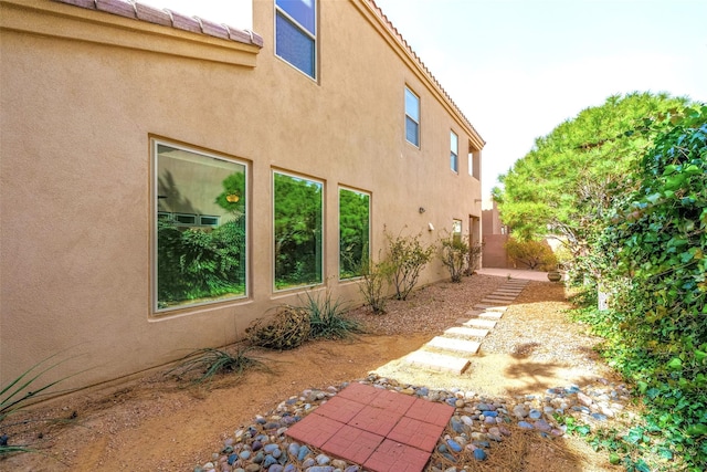 view of side of home featuring a tile roof and stucco siding